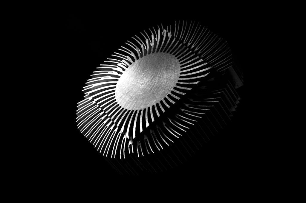 Close-up abstract image of a metallic heat sink with intricate patterns on a black background.