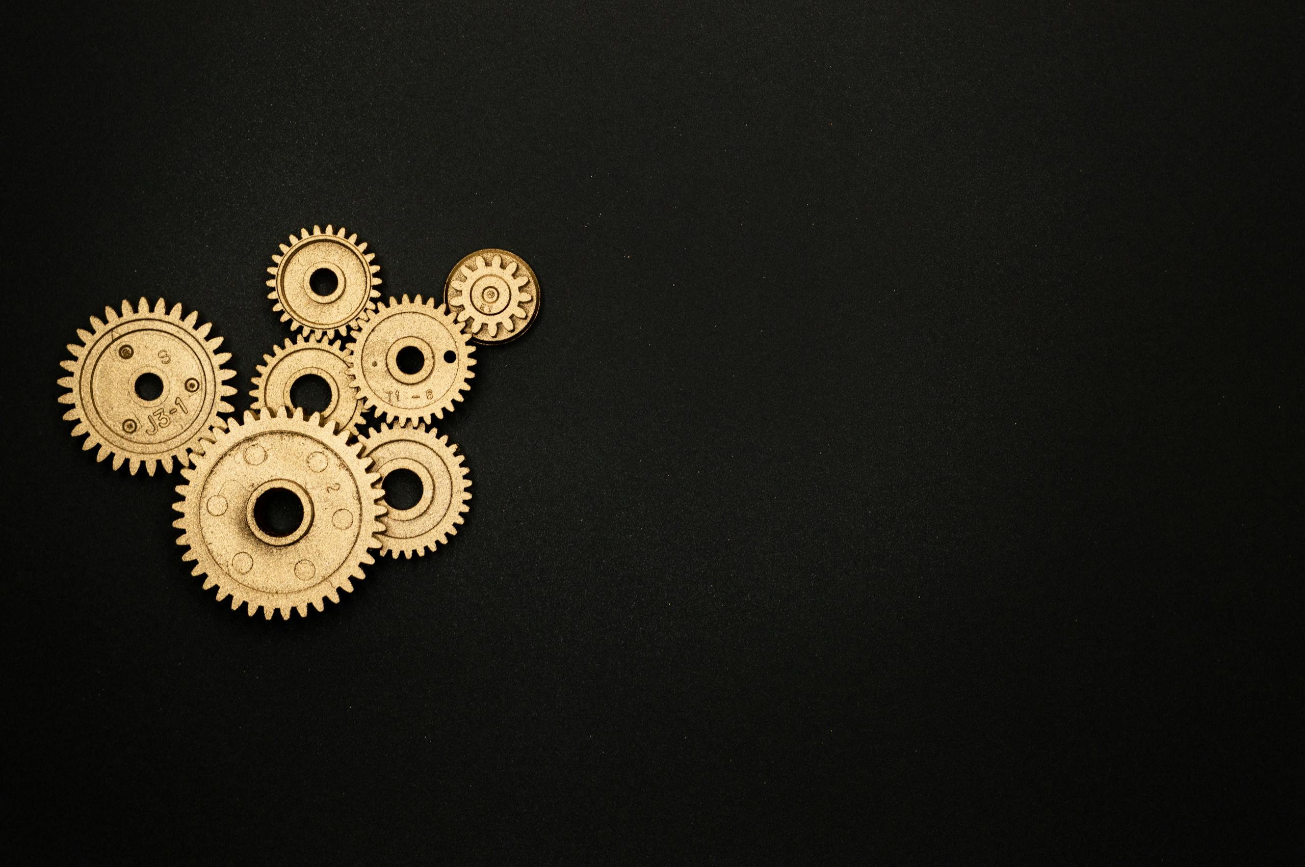 Gold gears on a black background representing industry, mechanics, and teamwork.