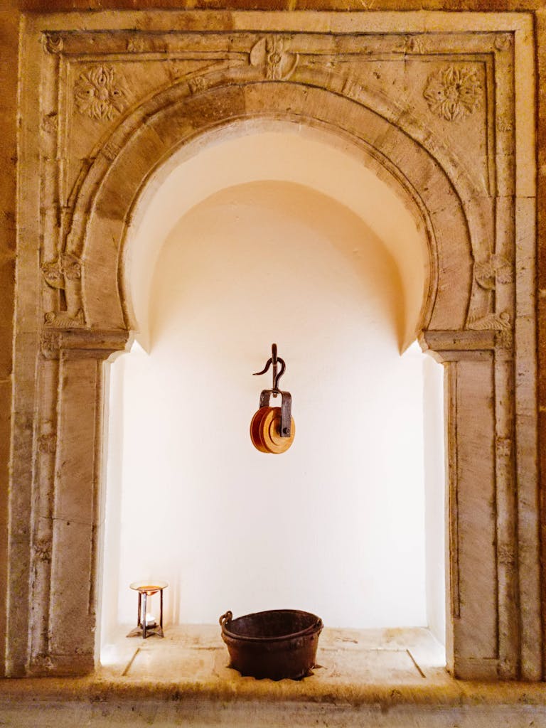 Stone arch niche with pulley system and bucket, historic architecture theme.